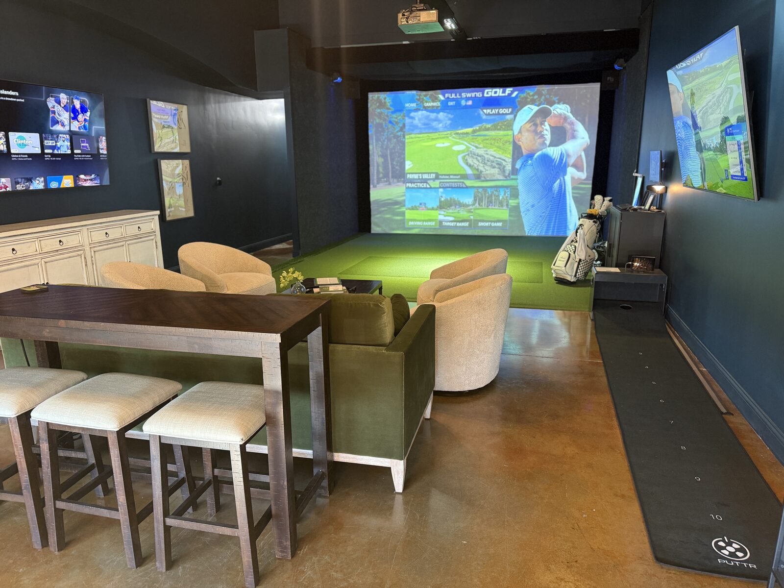 Golf simulator bay with putting mat and lounge seating