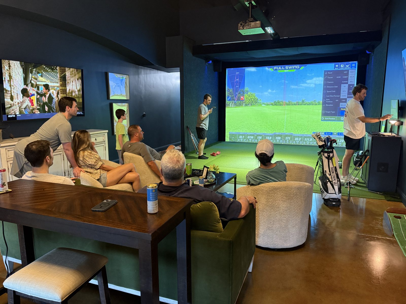 Friends and family gathered in the lounge watching a golfer on the Full Swing simulator
