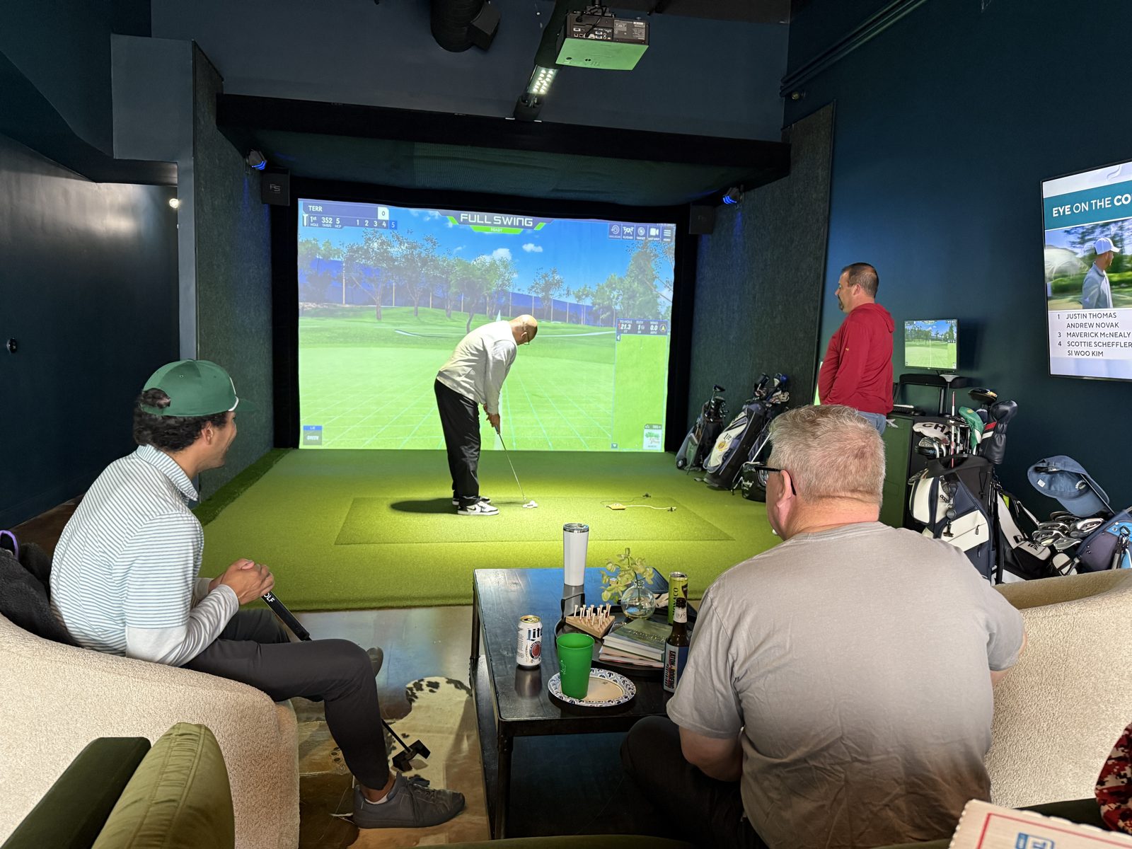 Golfer putting on the simulator green as friends look on